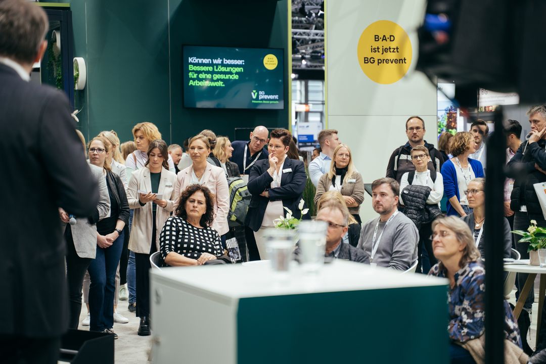 Besucher verfolgen eine Präsentation am Messestand